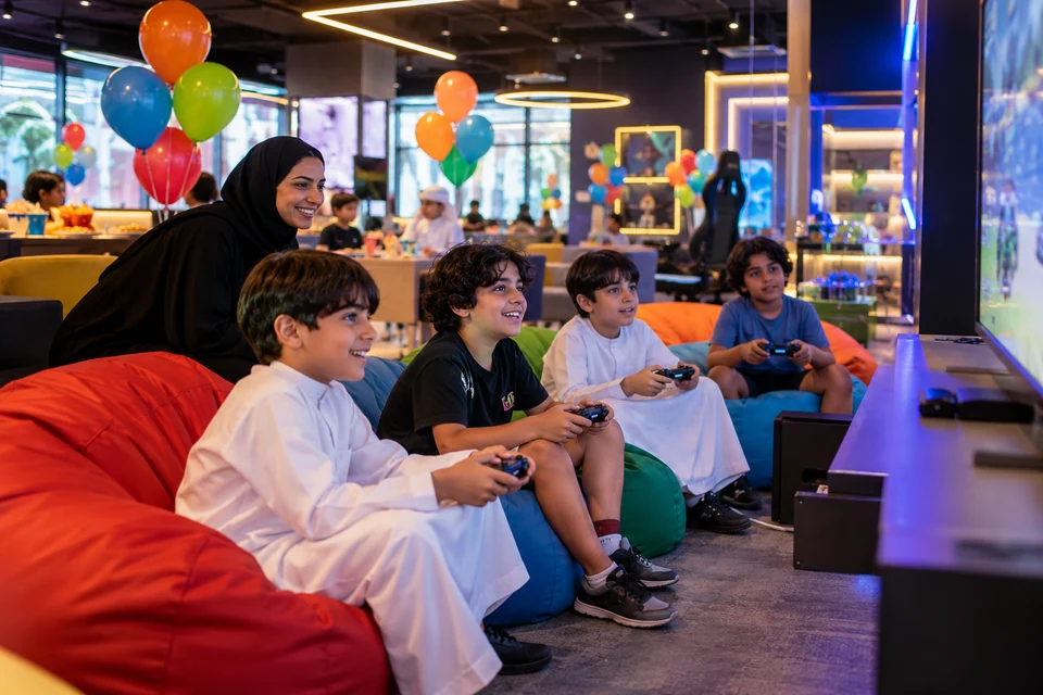Representative supervised birthday gathering around console gaming stations